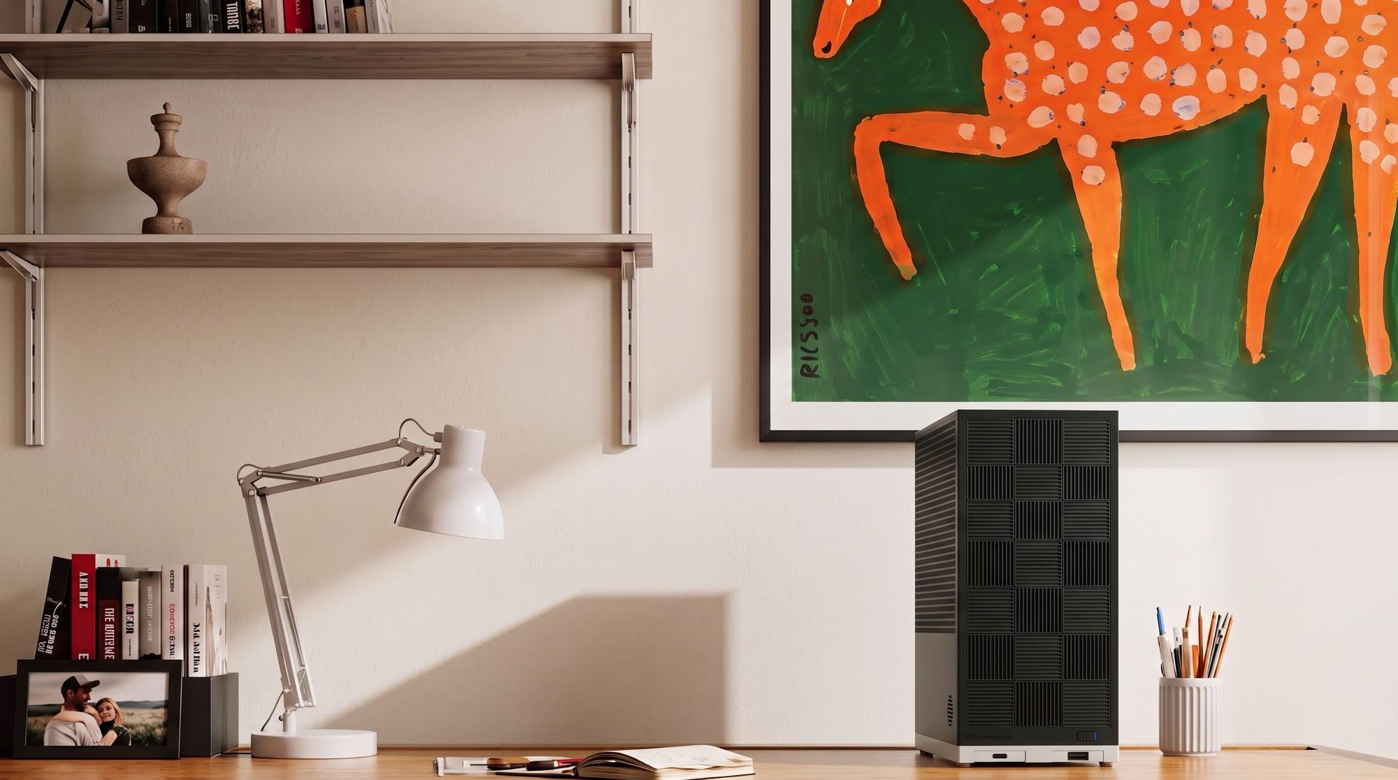 The Box on a home-office desk beside an angle-poise lamp and a stack of books, beneath a framed painting