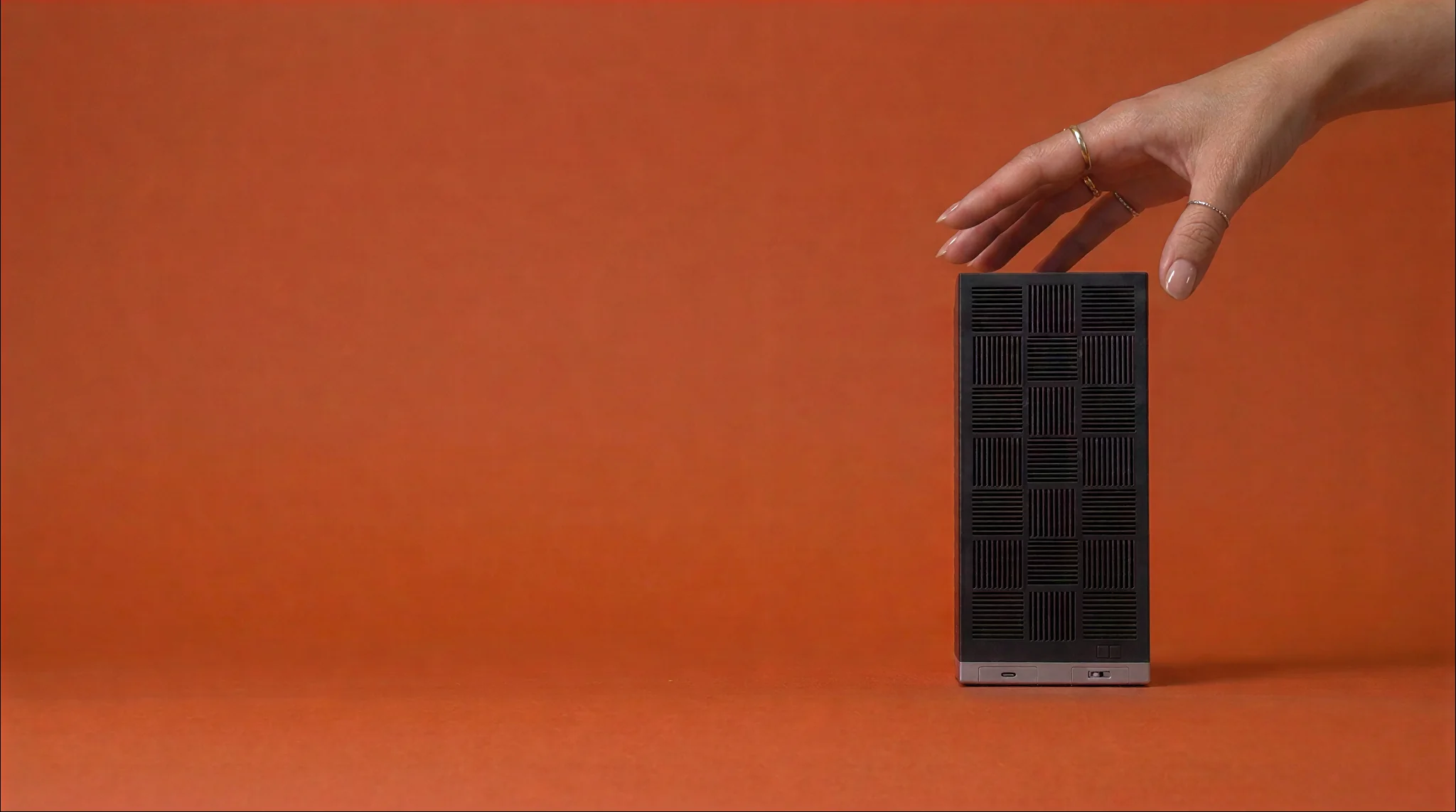 The Box on a red-orange backdrop, a hand reaching for its top